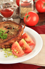 Piece of fried meat on plate on wooden table close-up