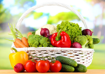 Fresh vegetables in white wicker basket on bright background