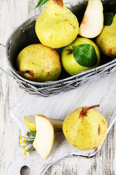 Pears in basket on board on wooden table