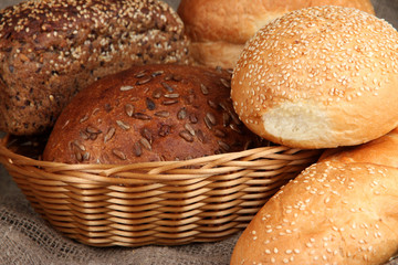 Baked bread in wicker basket on burlap background