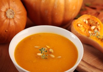 Bowl with pumpkin soup, baked butternut squash and pumpkins