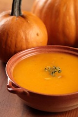 Bowl with pumpkin soup and pumpkins