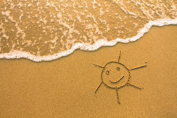 A sun drawn in the sand of a beach.