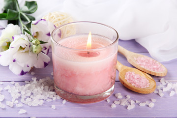 Beautiful pink candle with flowers on purple wooden background