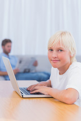 Little boy typing on laptop in living room