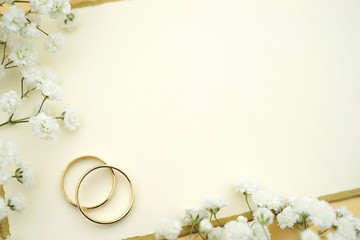 Elegante Hochzeitseinladung mit Eheringen aus Gold, einer Karte mit Textfreiraum und weissen...
