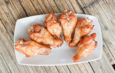 Fried chicken in a dish on bamboo flooring.