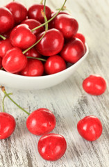 Cherry berries in bowl on wooden table close up