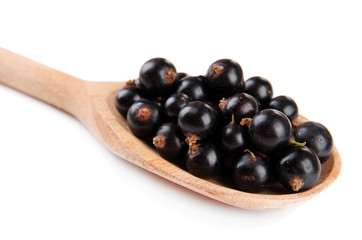 Black currant in wooden spoon isolated on white