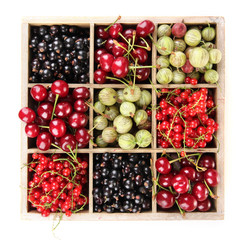 Different summer berries in wooden crate isolated on white