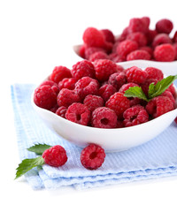 Ripe sweet raspberries in bowls, isolated on white