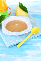 Tasty baby fruit puree and baby bottle on wooden table