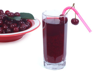 lass of cherry juice and plenty of ripe cherries isolated