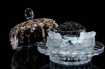 Black caviar in ice on a black isolated studio photo