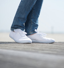 Legs in jeans and comfortable white shoes