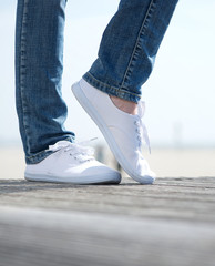 Woman legs in comfortable white shoes standing outdoors
