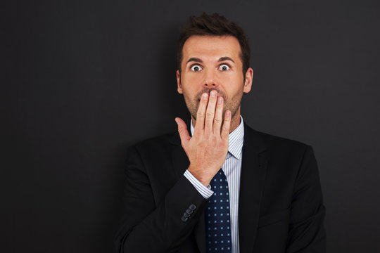 Fearful businessman covering his mouth - Powered by Adobe
