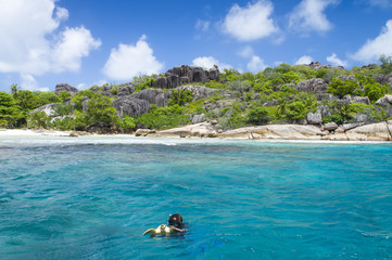 A snorkeler at an island coral reef with turtle. Seychelles.