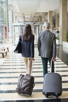Business couple pulling suitcases in a hotel lobby