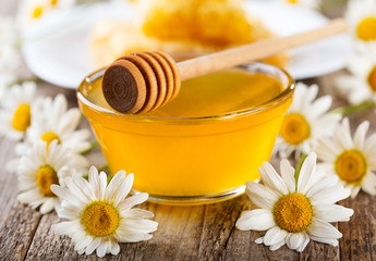 Obraz na płótnie Canvas jar of honey with daisy flowers
