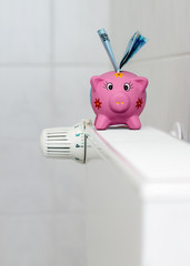 Piggy bank with radiator thermostat saving heating costs