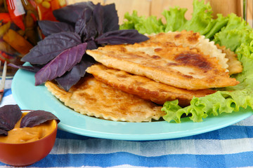 Tasty chebureks with fresh herbs on plate, close-up