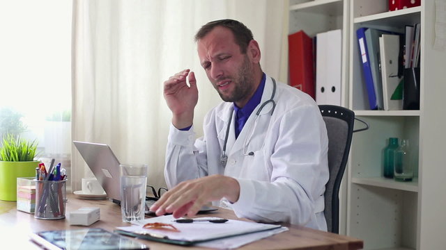 Male doctor taking pill for his headache