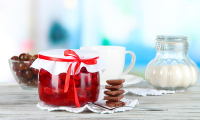 Yummy jam in bank on napkin on wooden table on room background