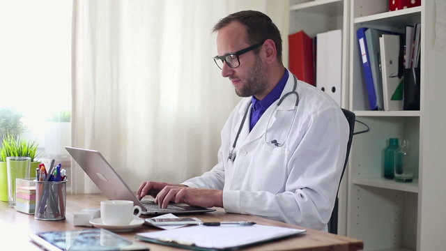 Young male doctor working on laptop