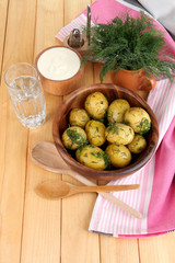 Boiled potatoes on wooden bowl near napkin on wooden table