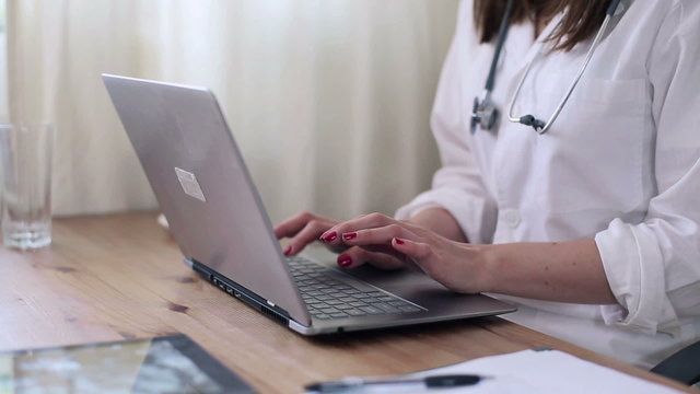 Female doctor hands working on laptop