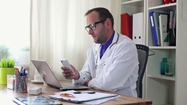 Male doctor sending sms in the office
