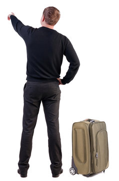 Back view of traveling business man with  suitcase pointing.