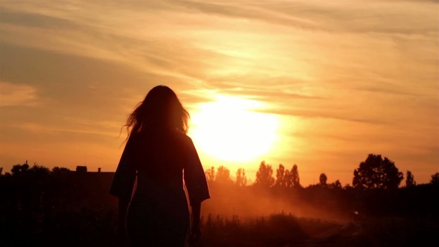 silhouette of a girl walking into the sunset