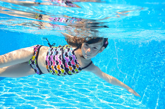 Happy active child swims freestyle in pool, underwater