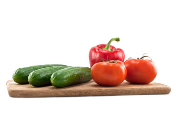 cucumbers, tomatoes and peppers on wooden board