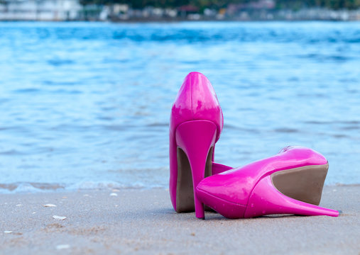Pair of pink high heels on the beach