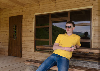 Man sitting in front of a wooden cabin