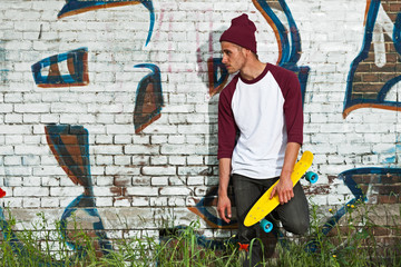 Obraz premium Hip cool urban fashion skateboarder with woolen hat posing in fr