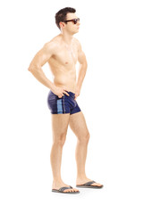 Fototapeta premium Full length portrait of a handsome guy in swimsuit posing