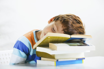 Tired schoolboy studying in home.