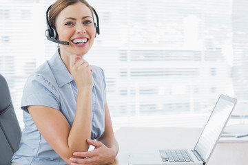 Laughing call centre agent wearing headset at her desk