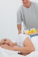 Obraz na płótnie Canvas Man bringing sleeping wife breakfast in bed
