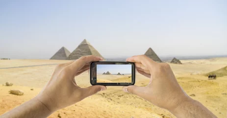 Gordijnen tourist holds up camera mobile at  pyramids © cunaplus