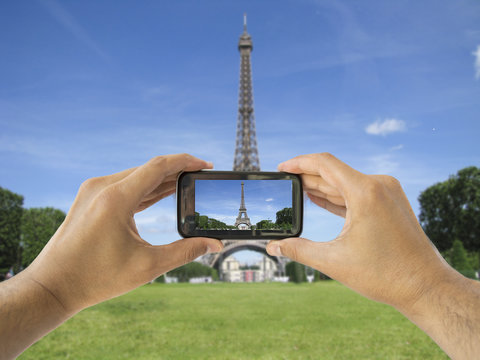 tourist holds up camera phone at   eiffel tower