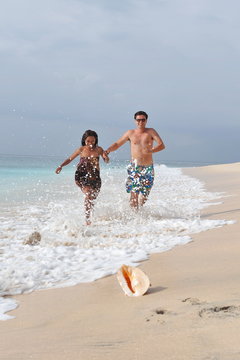 Couple running on beach. Young happy interracial couple