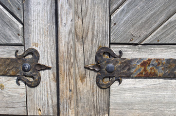Wrought iron door hinge on old wooden background