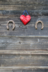 two rusty horseshoe and heart symbol on wooden wall
