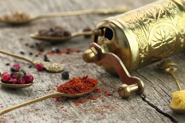 Wall murals Herbs Old spoons with spices and pepper grinder on wooden background