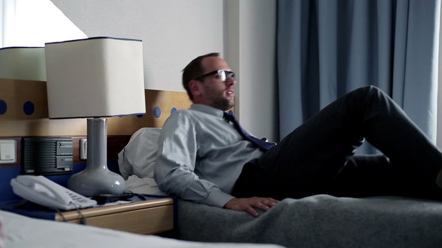 Tired businessman resting on bed in hotel room